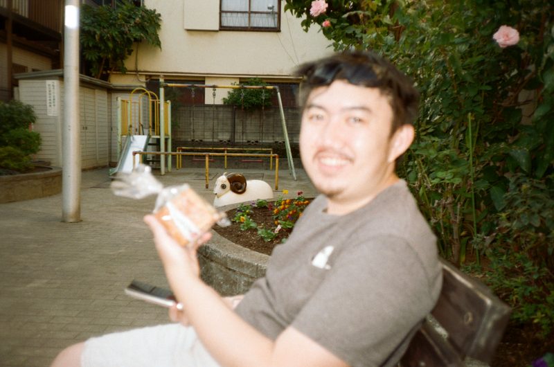 A photo of a man sitting in a park smiling