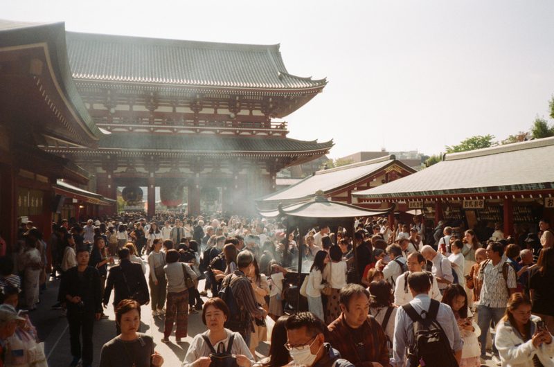 An image of Sensoji temple with many people around it and smoke rising from a small booth in the middle